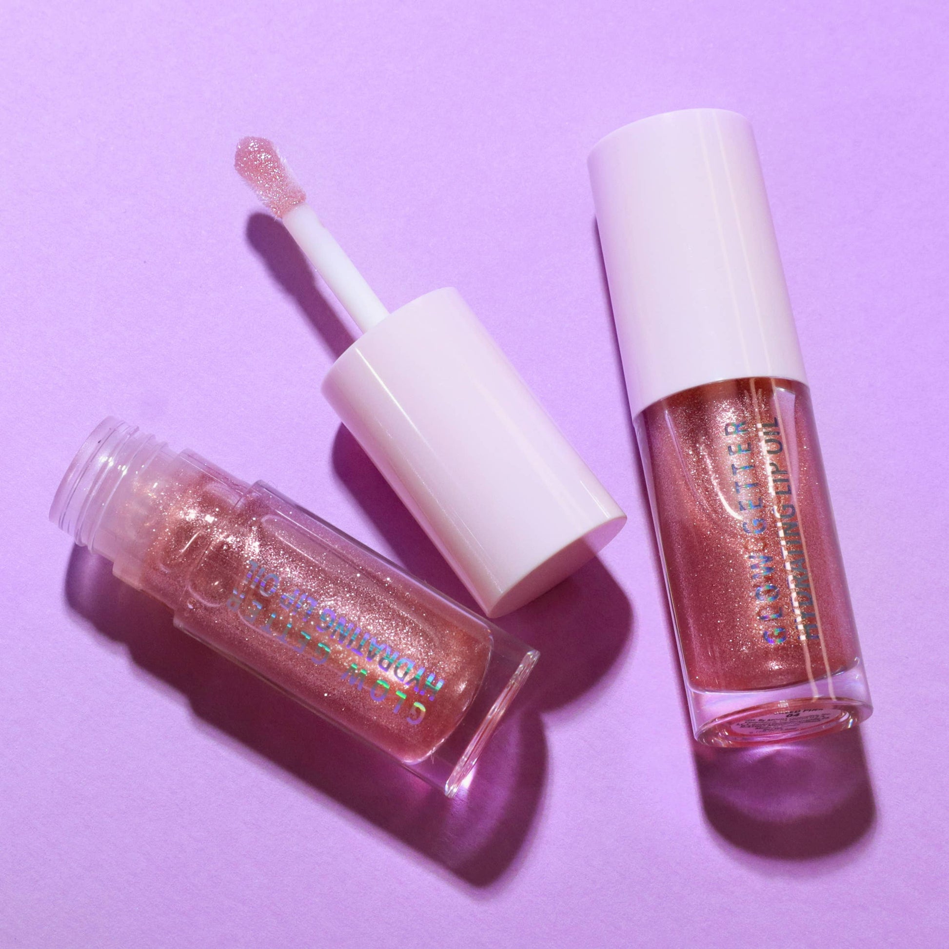 Two lip glosses on a purple background
