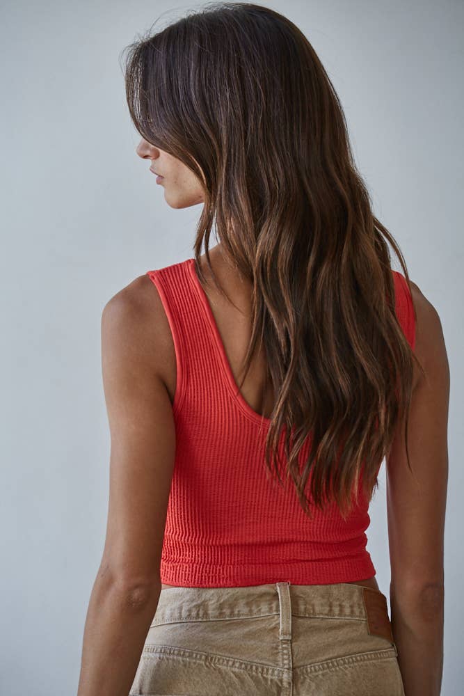 Woman wearing a red tank top against a gray background
