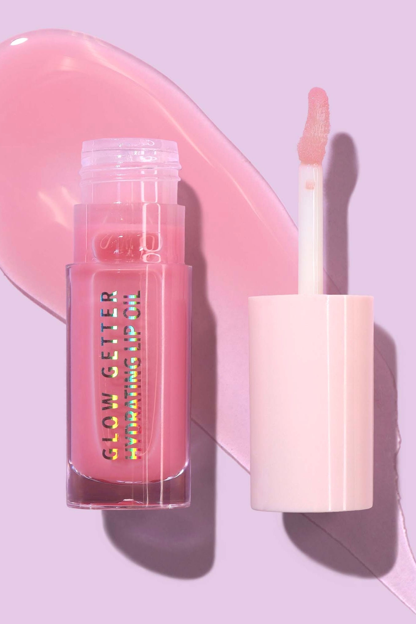 Lip gloss with applicator on a pink heart-shaped background