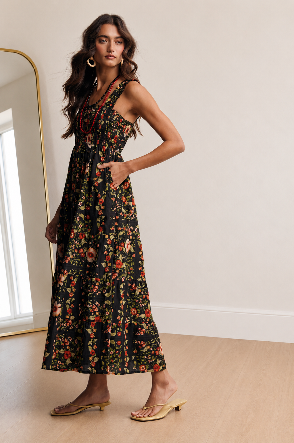 Side view of The Folk Tale black floral maxi dress showing its hidden pocket and tiered silhouette