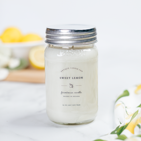 Sweet Lemon 16 oz soy candle close-up on marble surface for clean fresh citrus home fragrance.
