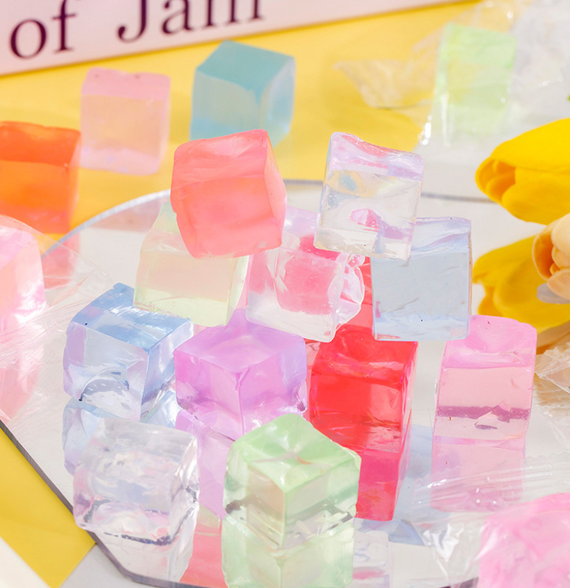 Colorful jelly cubes in a clear container with a yellow background