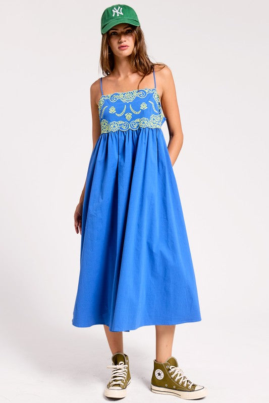 Bright blue midi dress with embroidered-inspired contrast bodice detail, adjustable straps, and side pockets.