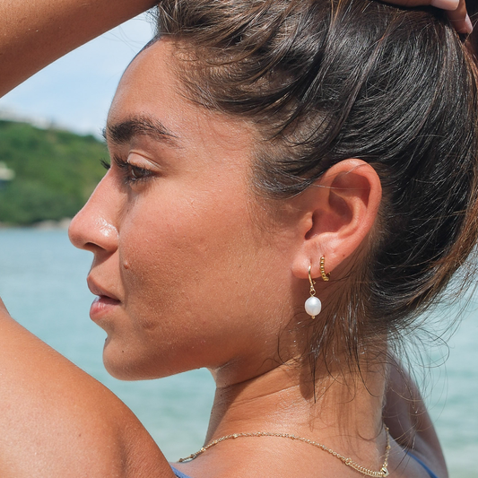 Woman with pearl earrings by a body of water