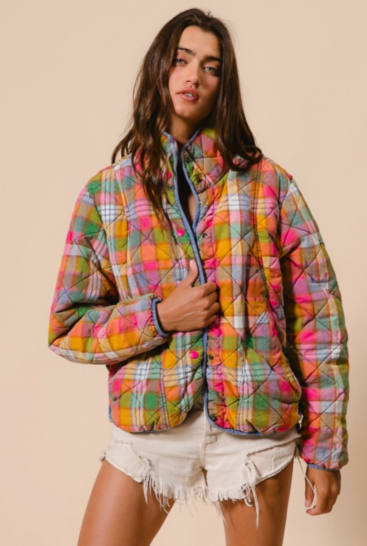 Woman wearing a colorful plaid jacket against a beige background