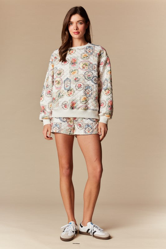 Woman wearing a floral sweatshirt and shorts set on a beige background