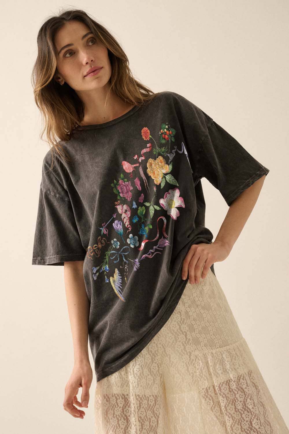 Woman wearing a dark gray t-shirt with colorful floral graphic on a plain background 