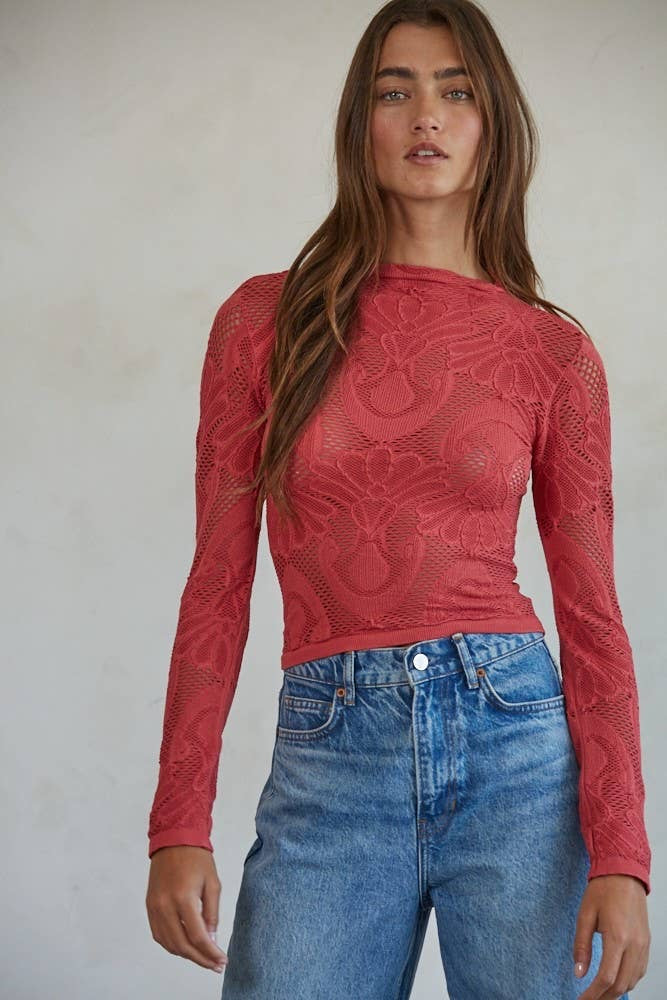 Woman wearing a crimson floral lace long sleeve top styled with high-waisted denim jeans