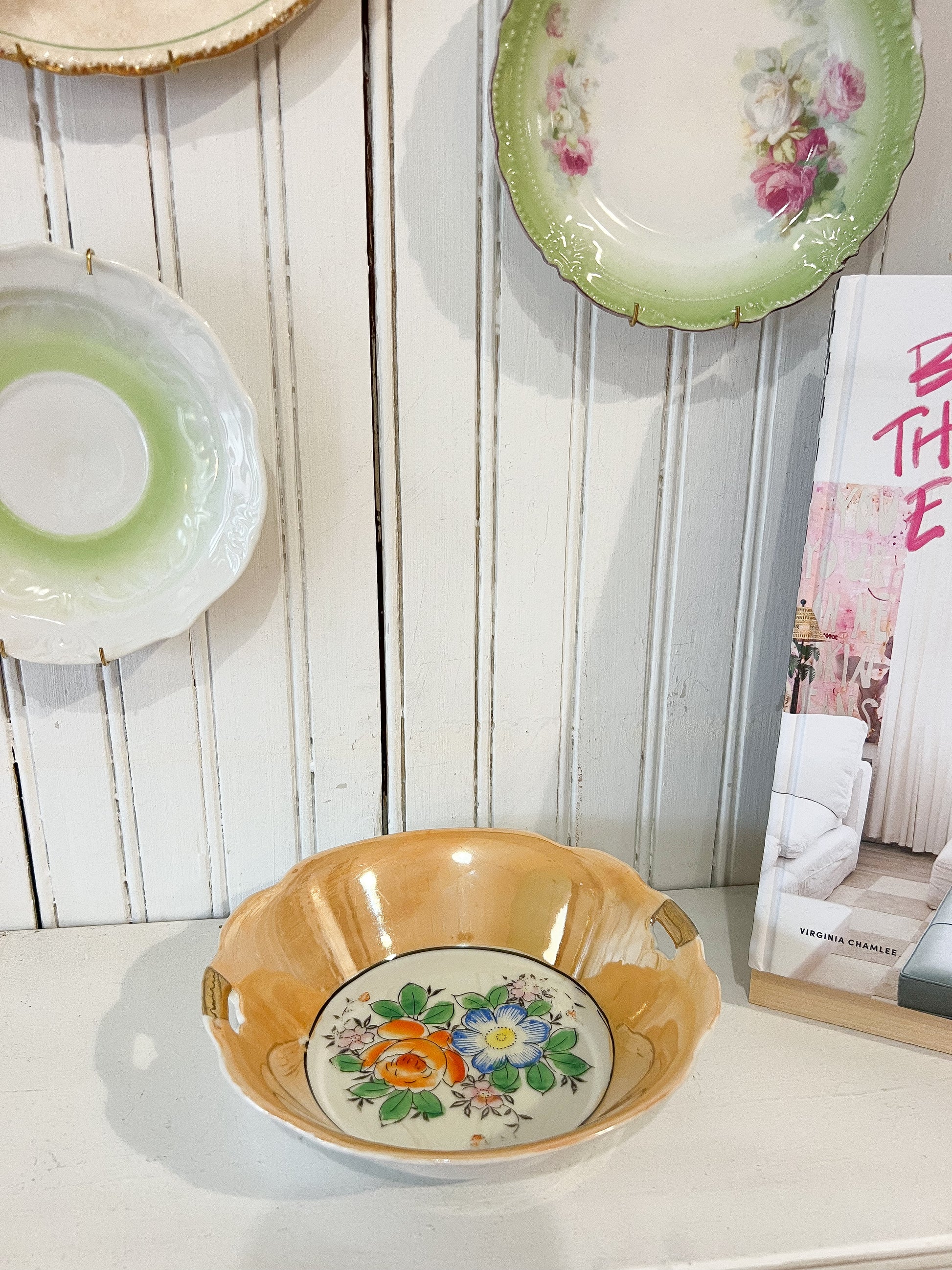 Decorative ceramic bowl with floral design on a white surface with a wooden panel background.