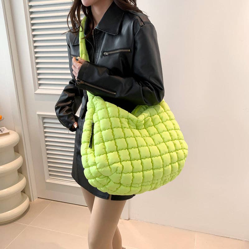 Person holding a bright green quilted handbag indoors.