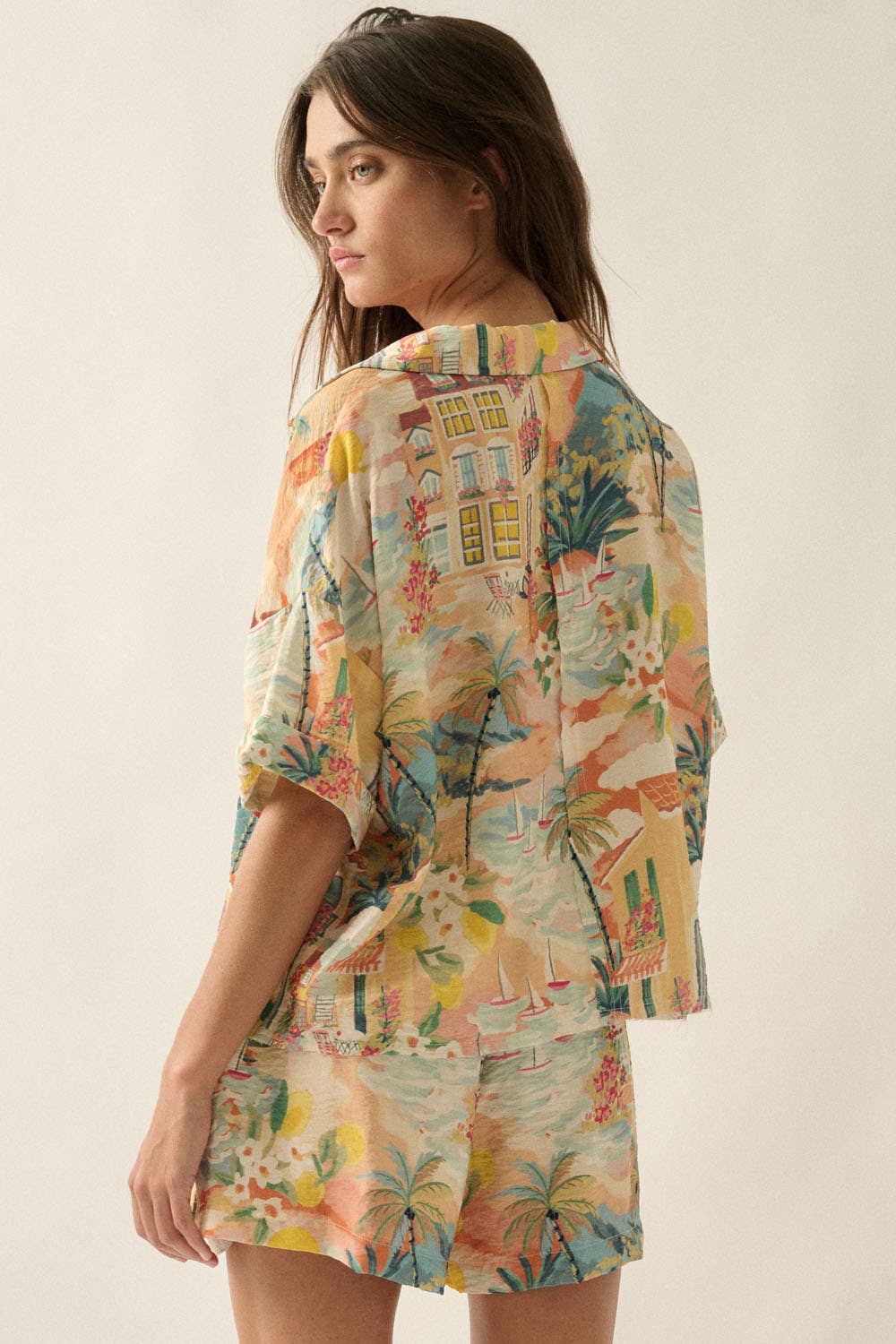 Woman wearing a colorful tropical print outfit on a plain background