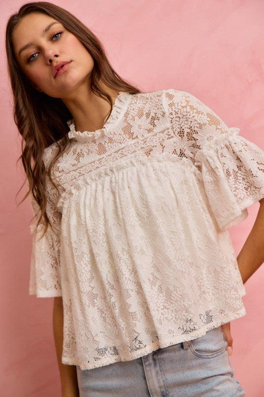 Woman wearing a lace blouse against a pink background