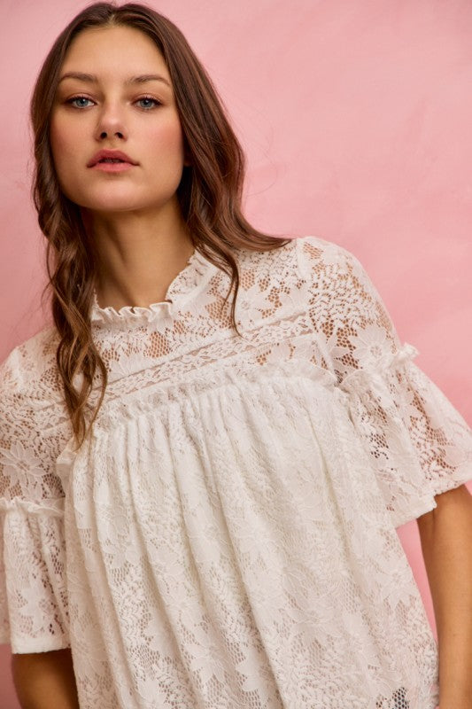 Woman wearing a white lace dress against a pink background