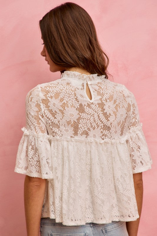 Woman wearing a white lace blouse against a pink background