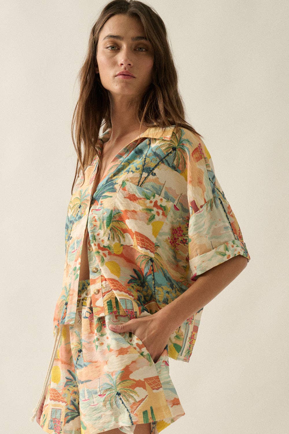 Woman wearing a colorful tropical print top against a plain background