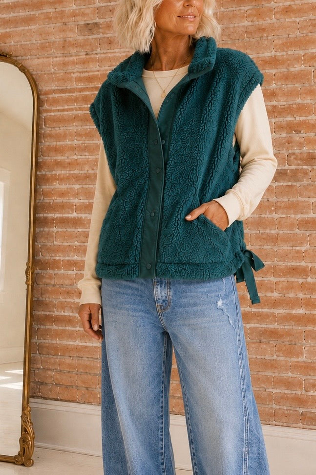     Woman wearing The Timberline Sherpa Vest in Deep Spruce with a cream long-sleeve top and wide-leg jeans.