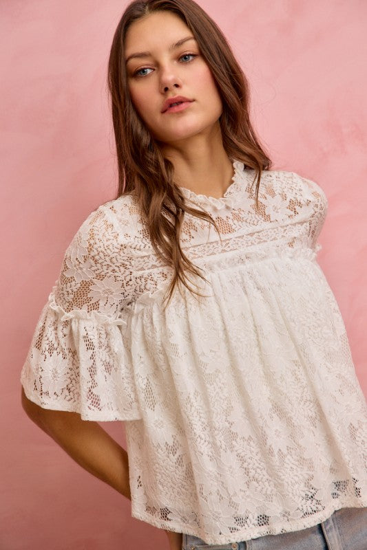 Woman wearing a white lace blouse against a pink background