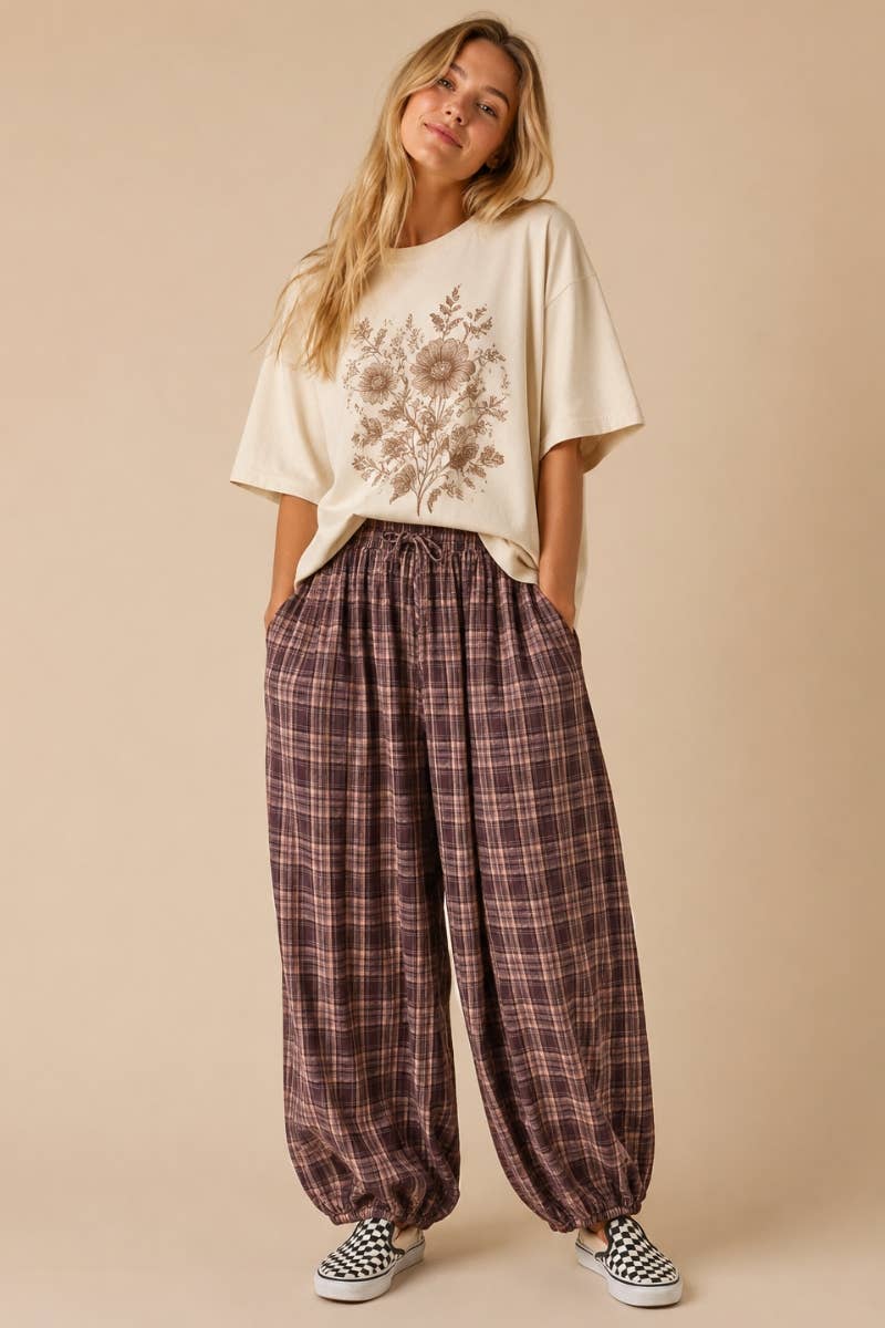 Woman wearing a floral top and plaid pants on a beige background