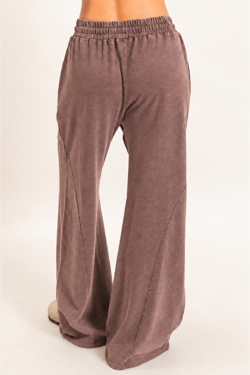 A pair of wide-leg lounge pants in a dusty mauve-brown color, shown on a model from the back against a plain light background.