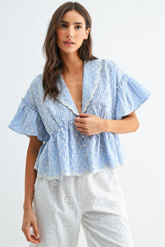 Woman wearing a blue checkered top with ruffled sleeves on a white background