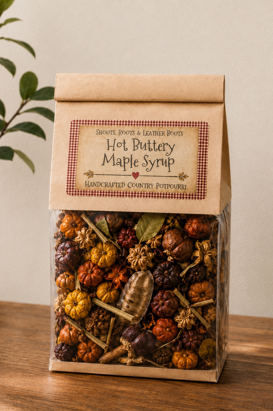 A clear plastic bag filled with decorative hot butterscotch maple syrup pieces and topped with a kraft paper lid labeled 'Hot Butterscotch Maple Syrup' by Sweet's Roots & Leather Potts, set on a wooden surface against a light wall.