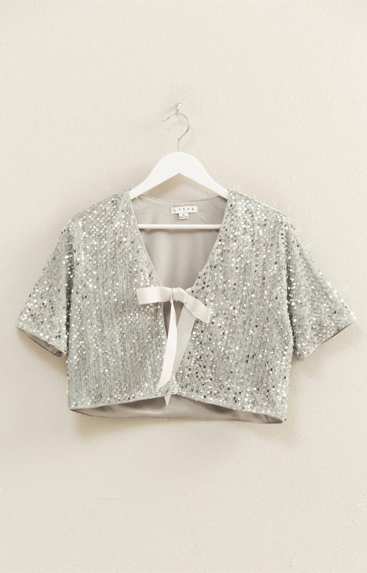 Silver sequin tie-front cropped top layered over white tank on model.