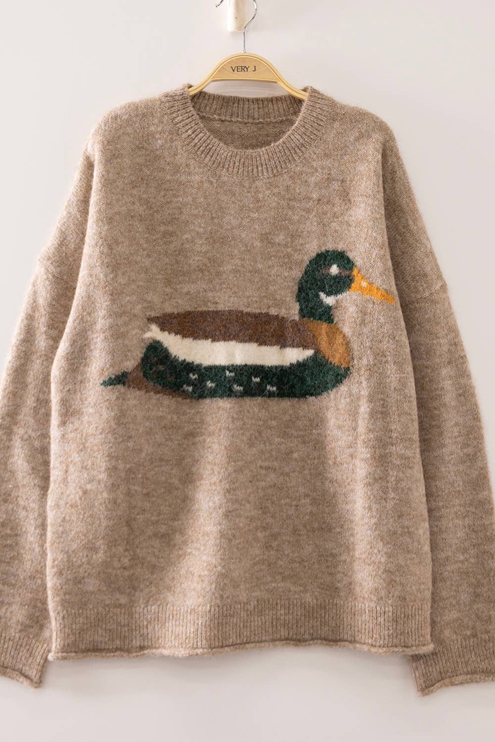 Beige sweater with a duck design on a hanger against a white background