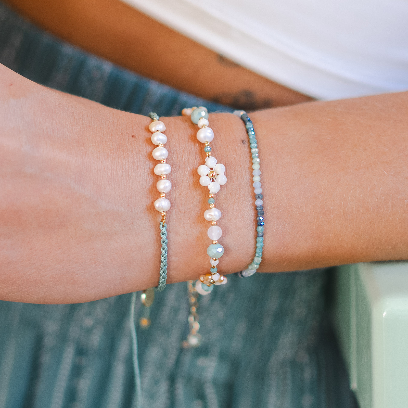 Close-up of a wrist wearing multiple beaded bracelets with a blurred background