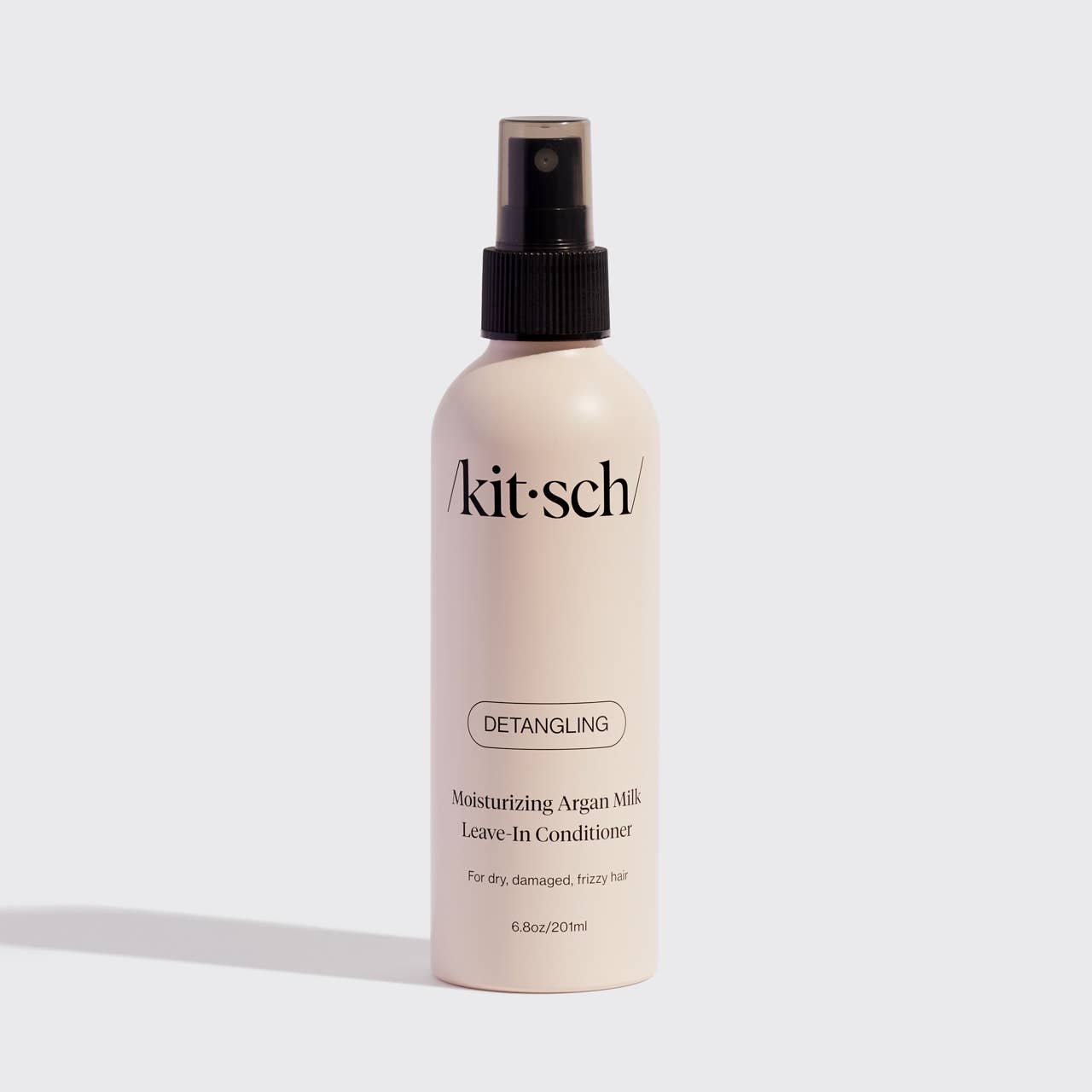 Kitsch Moisturizing Argan Milk Leave-In Conditioner bottle with black spray top on neutral background.
