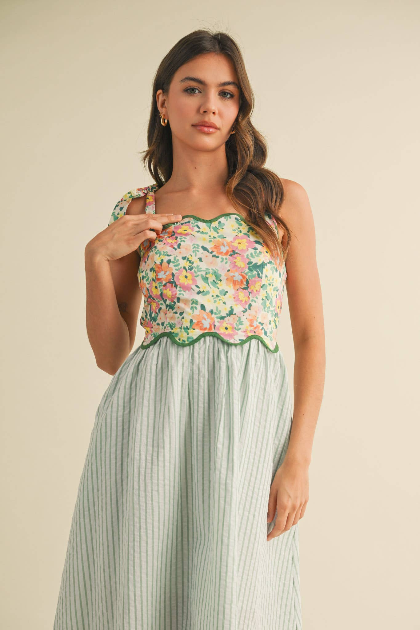 Woman wearing a floral top and striped skirt on a beige background