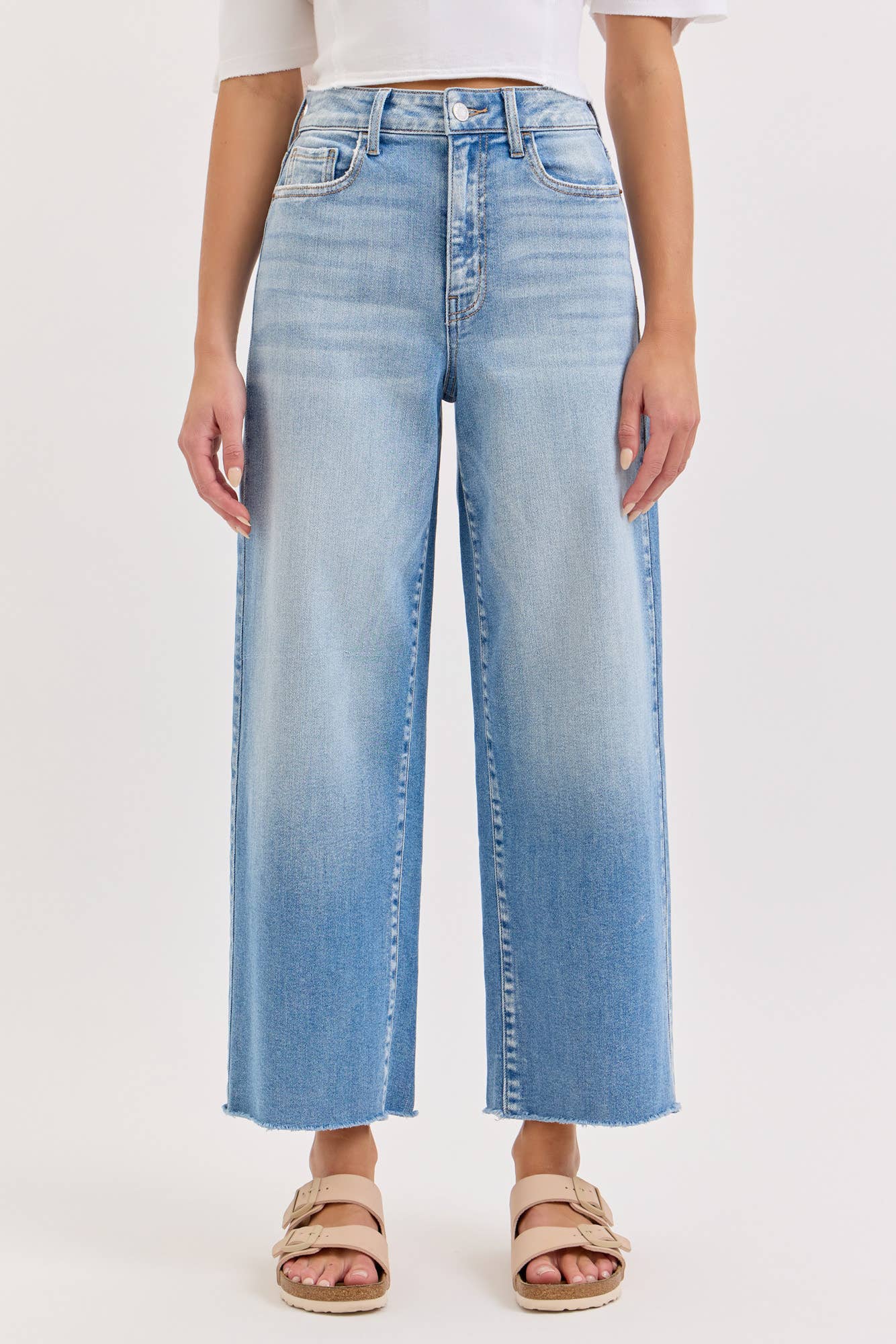 Person wearing light blue wide-leg jeans on a white background
