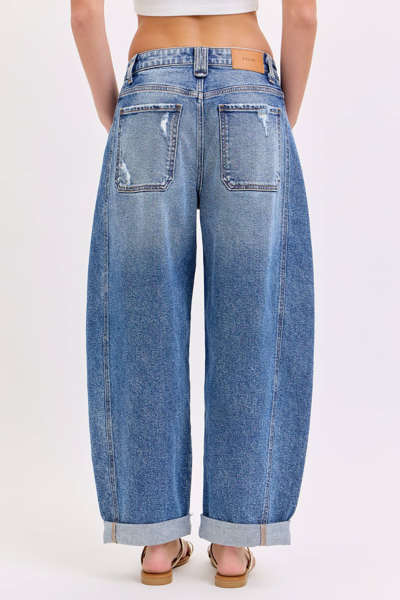 Barrel blue jeans worn by a person on a white background