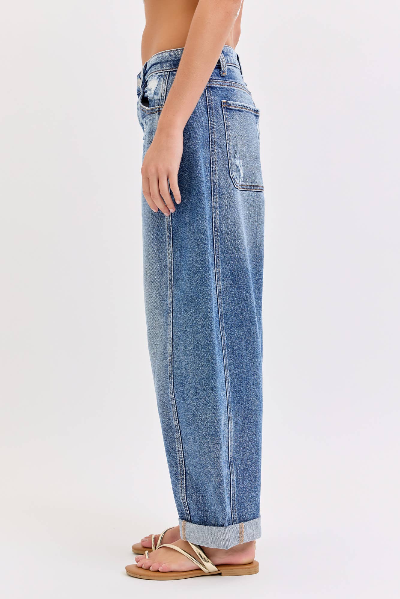 Side view of barrel Blue jeans worn by a person on a white background