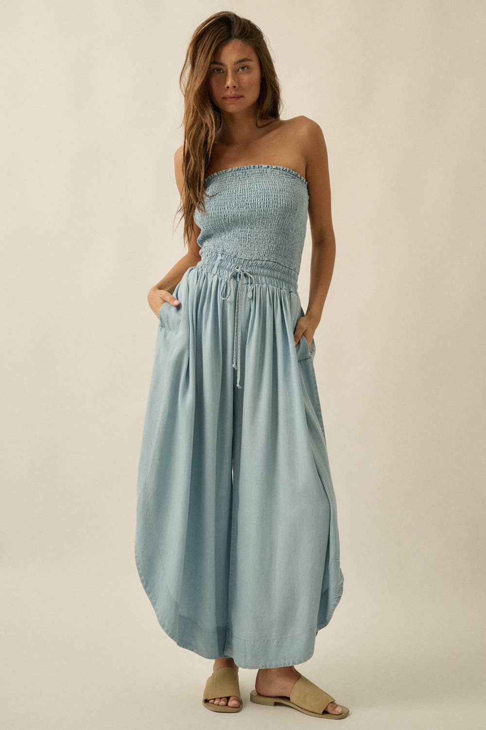 Woman wearing a light blue strapless dress against a beige background