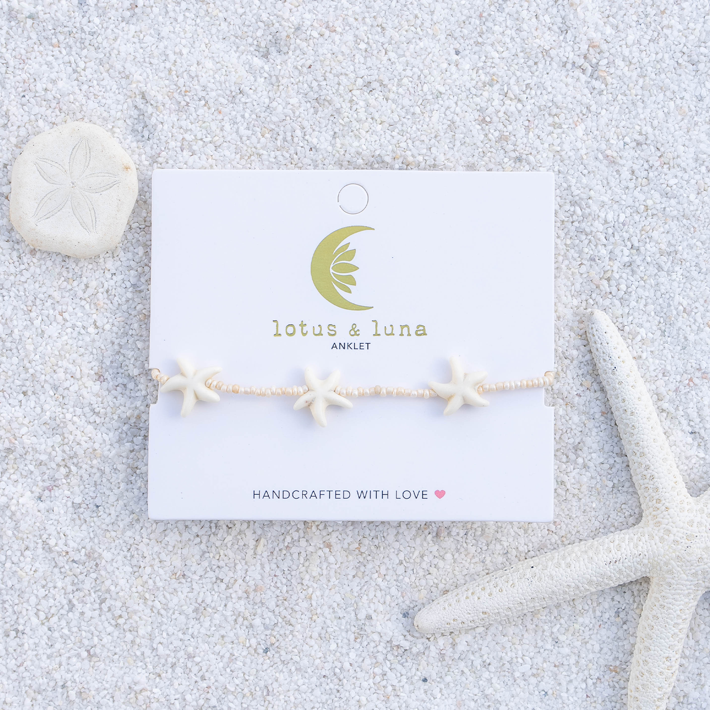 Starfish anklet on a 'lotus & luna' branded card with sand and starfish decorations.