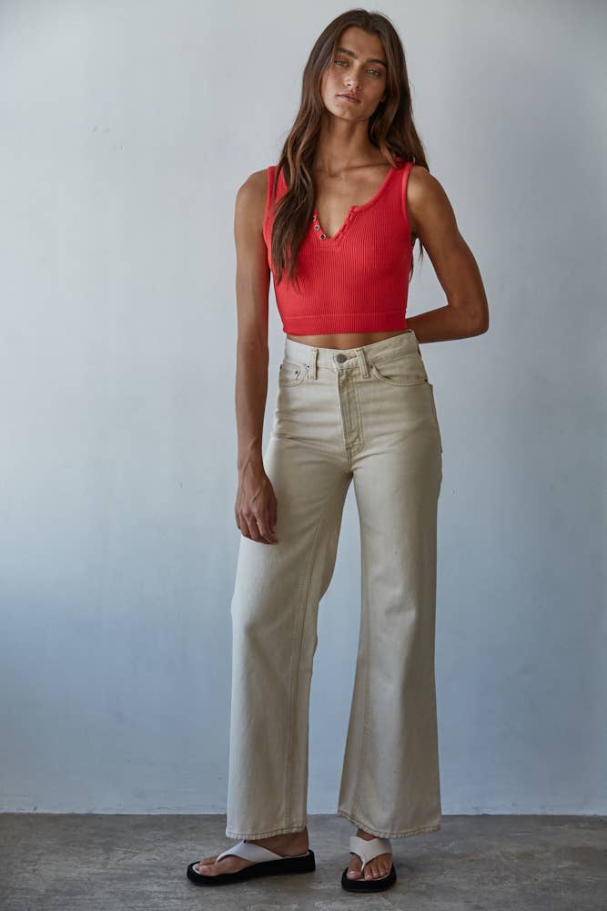 Woman wearing a red top and beige pants against a plain background