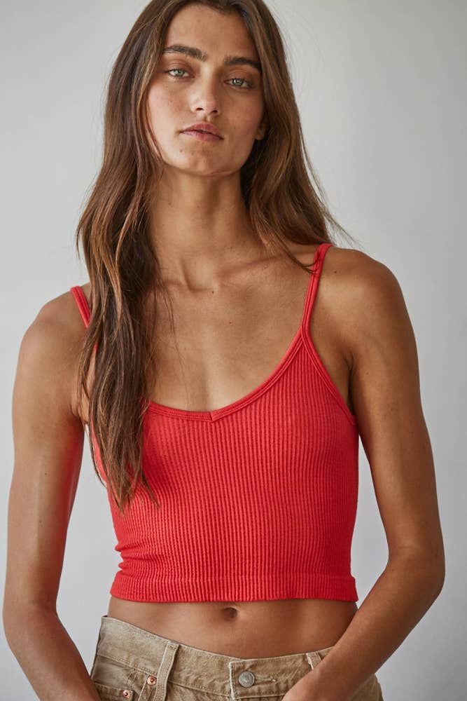 Woman wearing a red ribbed tank top against a neutral background